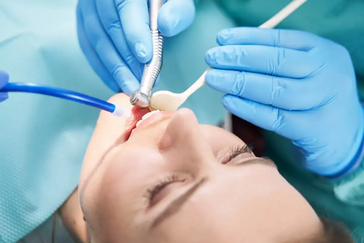 Dentist performing laser treatment on patient's tooth during dental procedure.